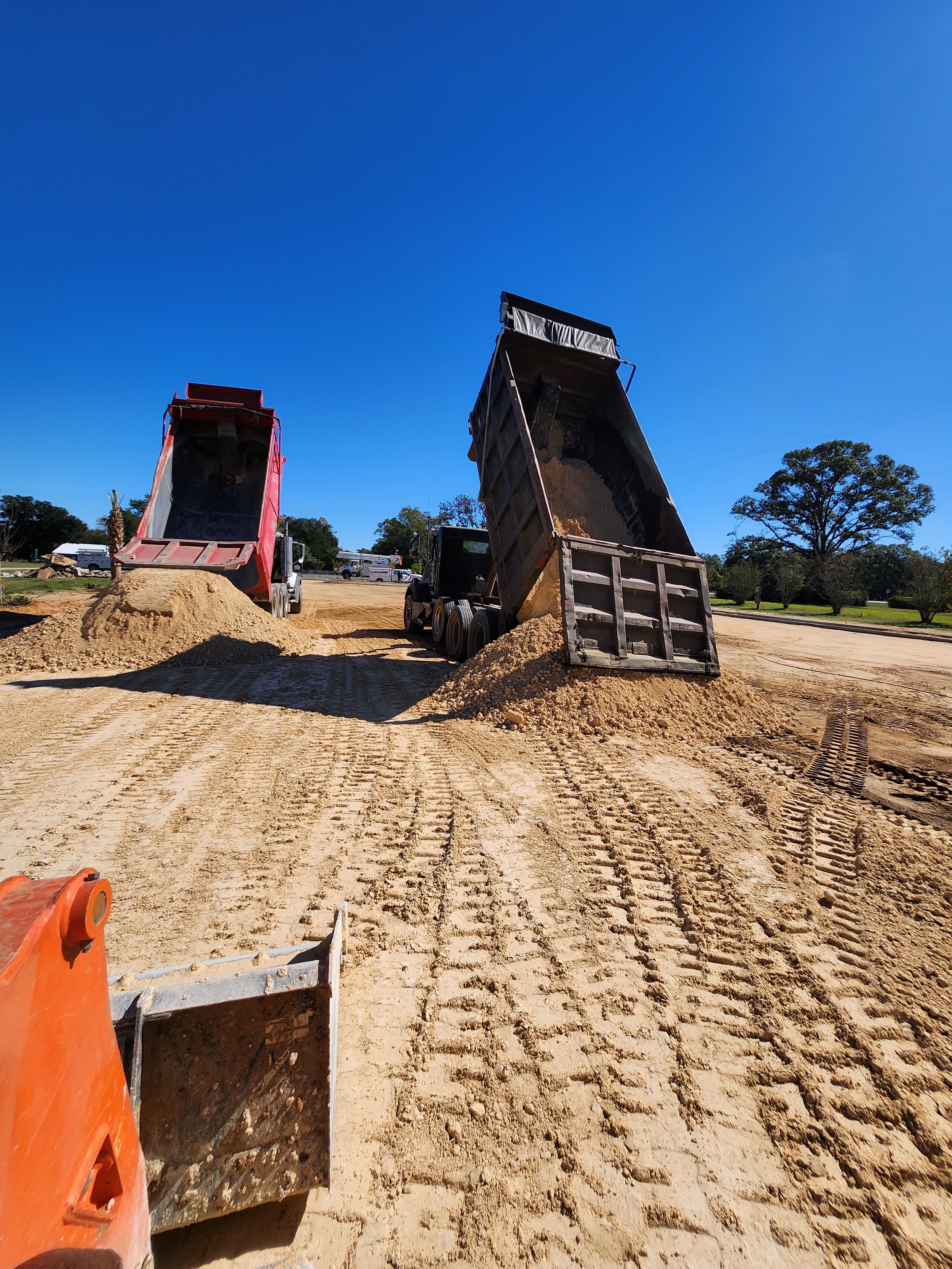 Dump trucks unloading dirt on a construction site during the day.