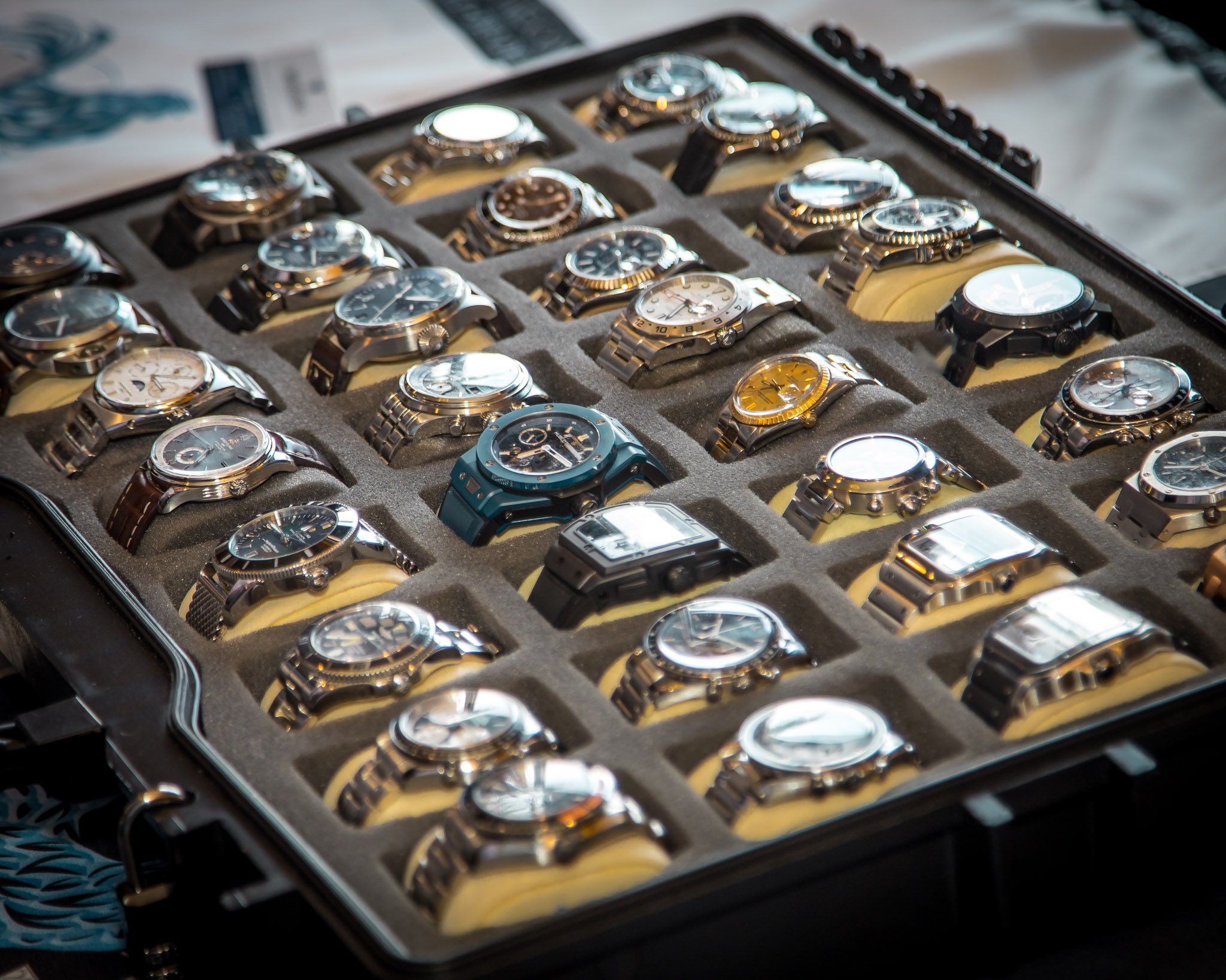 A collection of wristwatches in a foam-lined watch case, with a smartphone nearby.