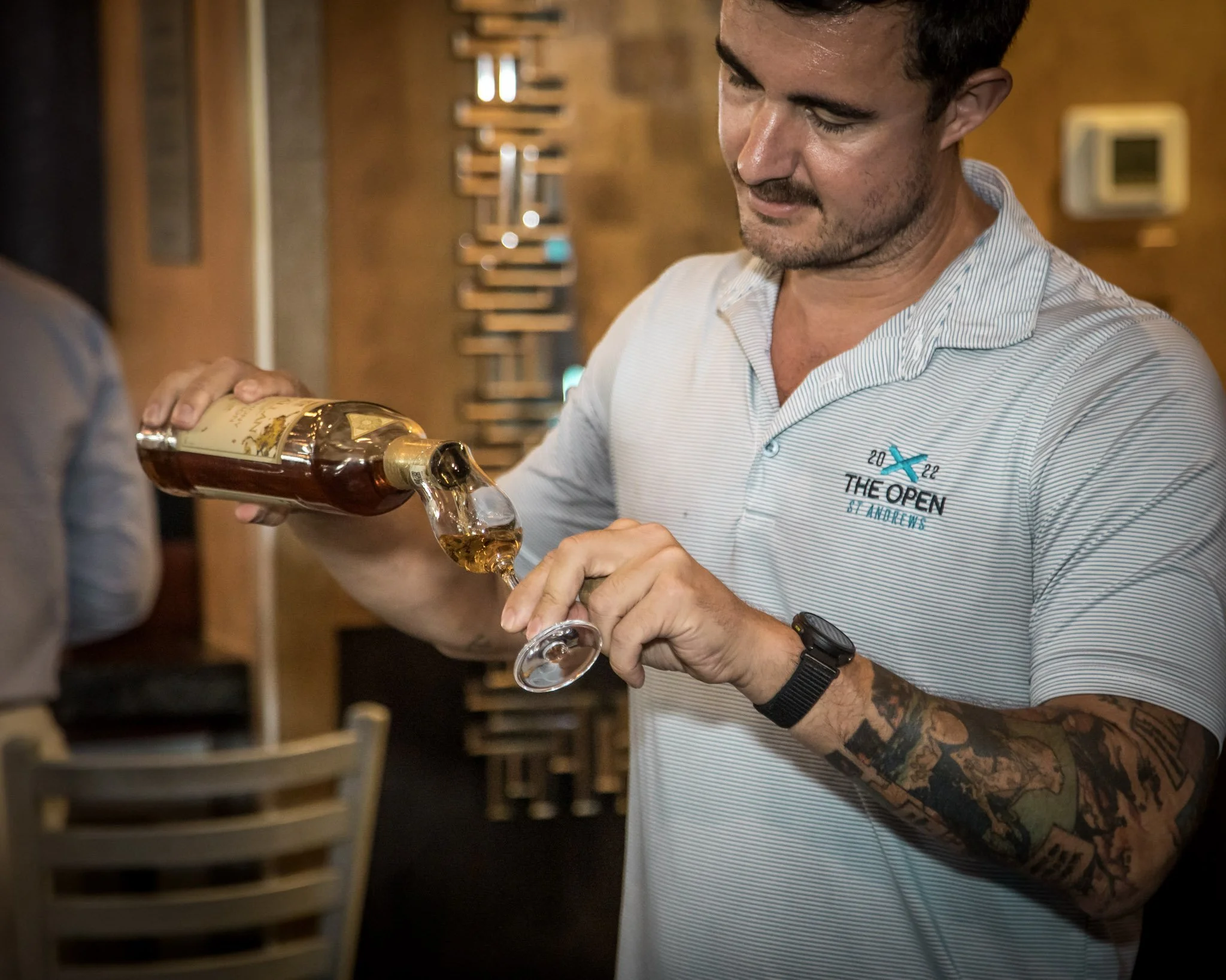 Man pouring a drink from a bottle into a glass at a bar