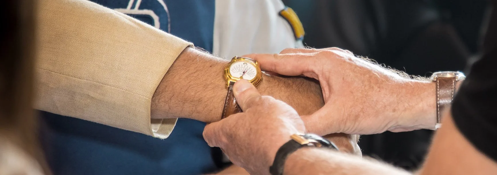 Person adjusting a gold watch on another person's wrist during a handover or greeting.