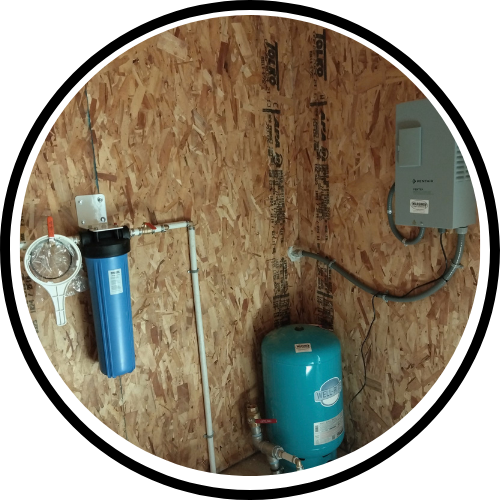 Water filtration and softening system with blue tank and wall-mounted control box in a wood-paneled utility area