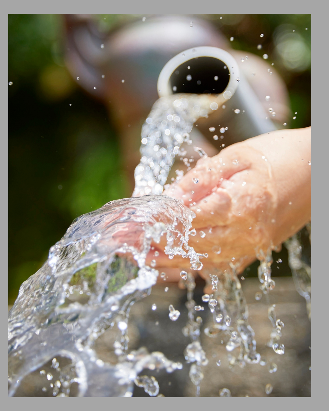 Person running water over their hands from a faucet outdoors.