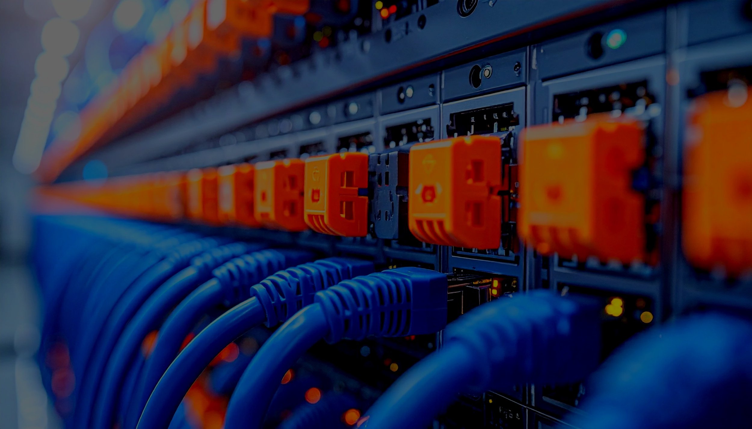 Close-up of a server rack with blue Ethernet cables plugged into orange ports, in a data center.