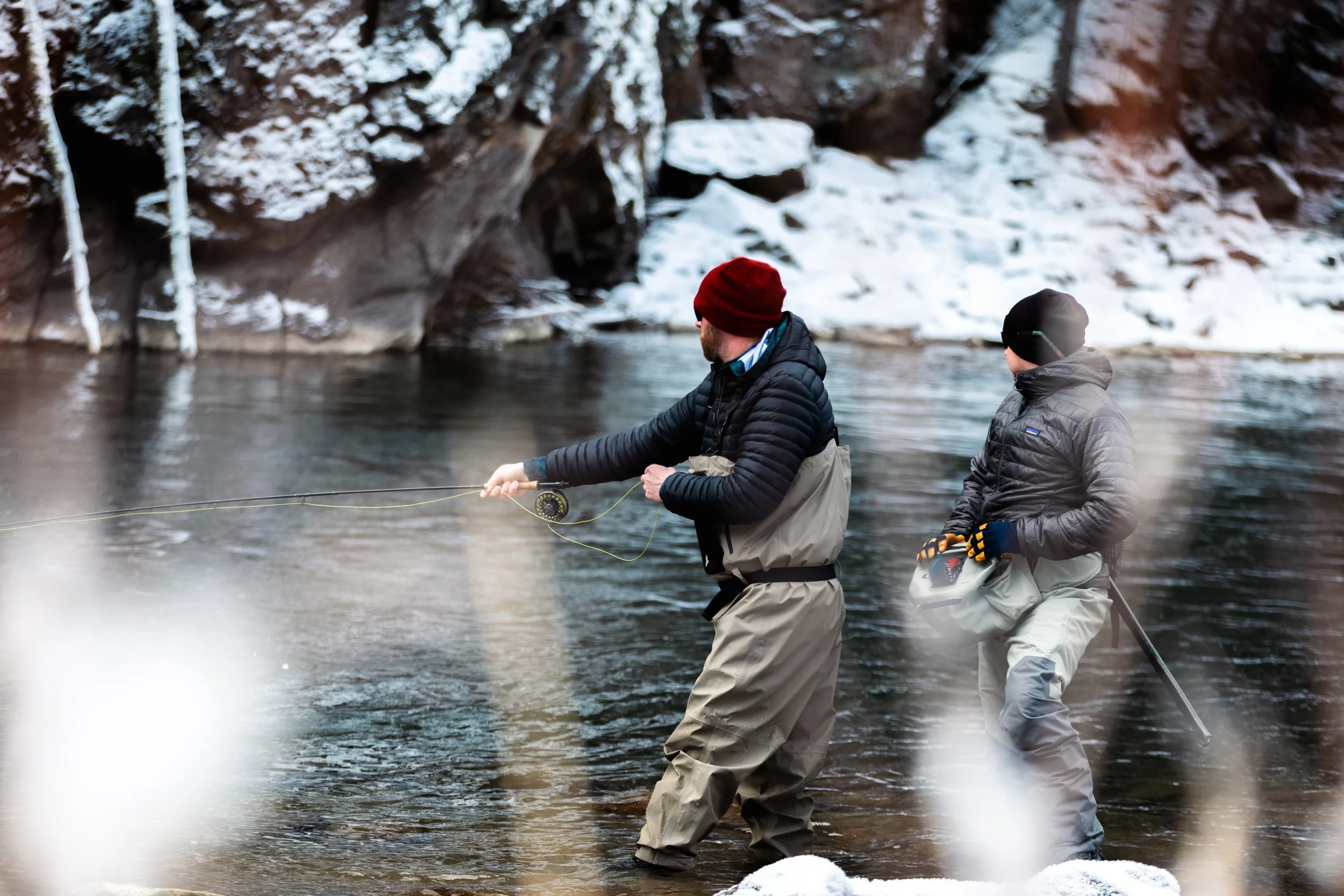 man casting into a river with snowy banks