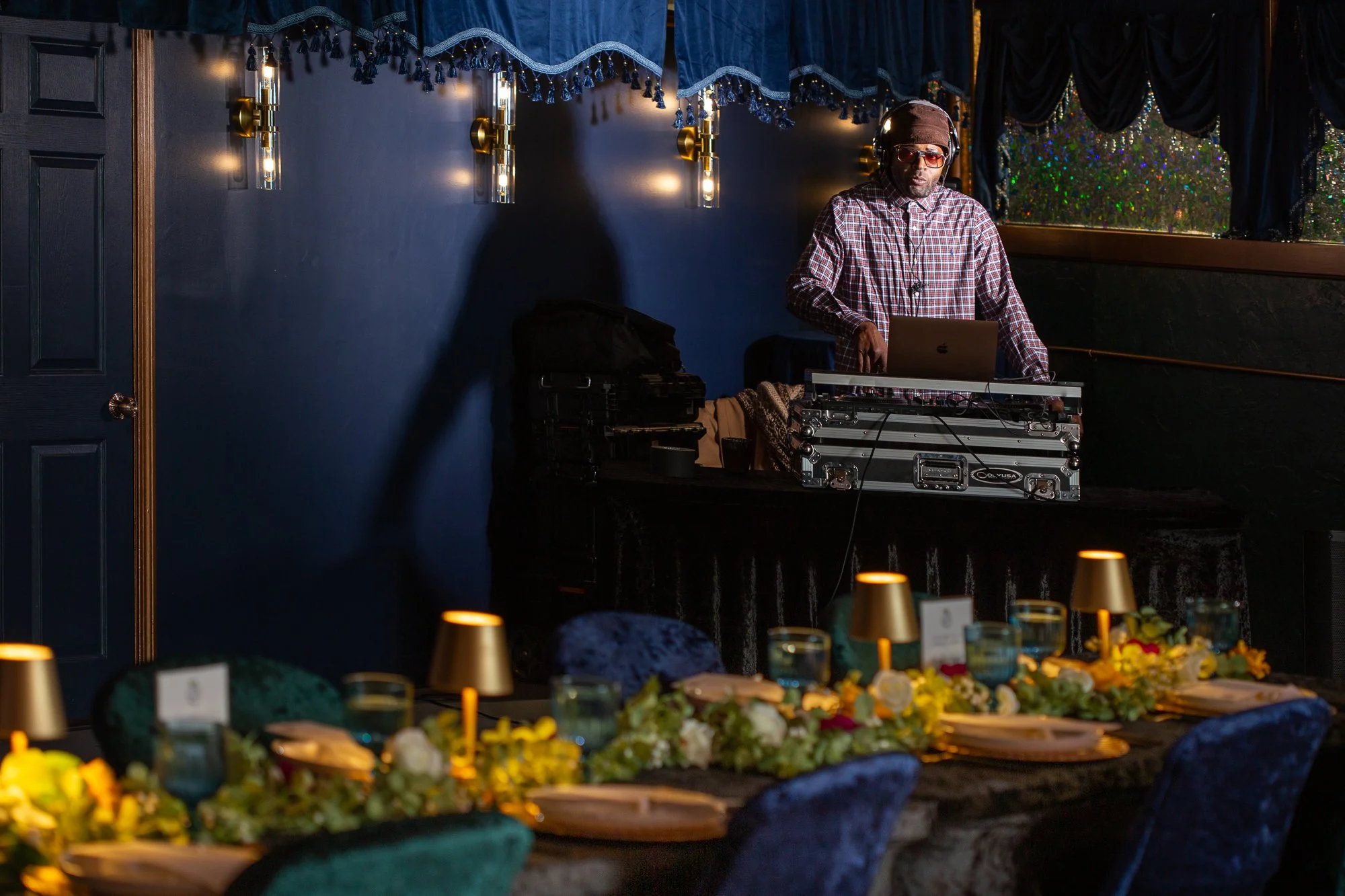 DJ performing at a decorated event space with a table set for a banquet in the foreground.