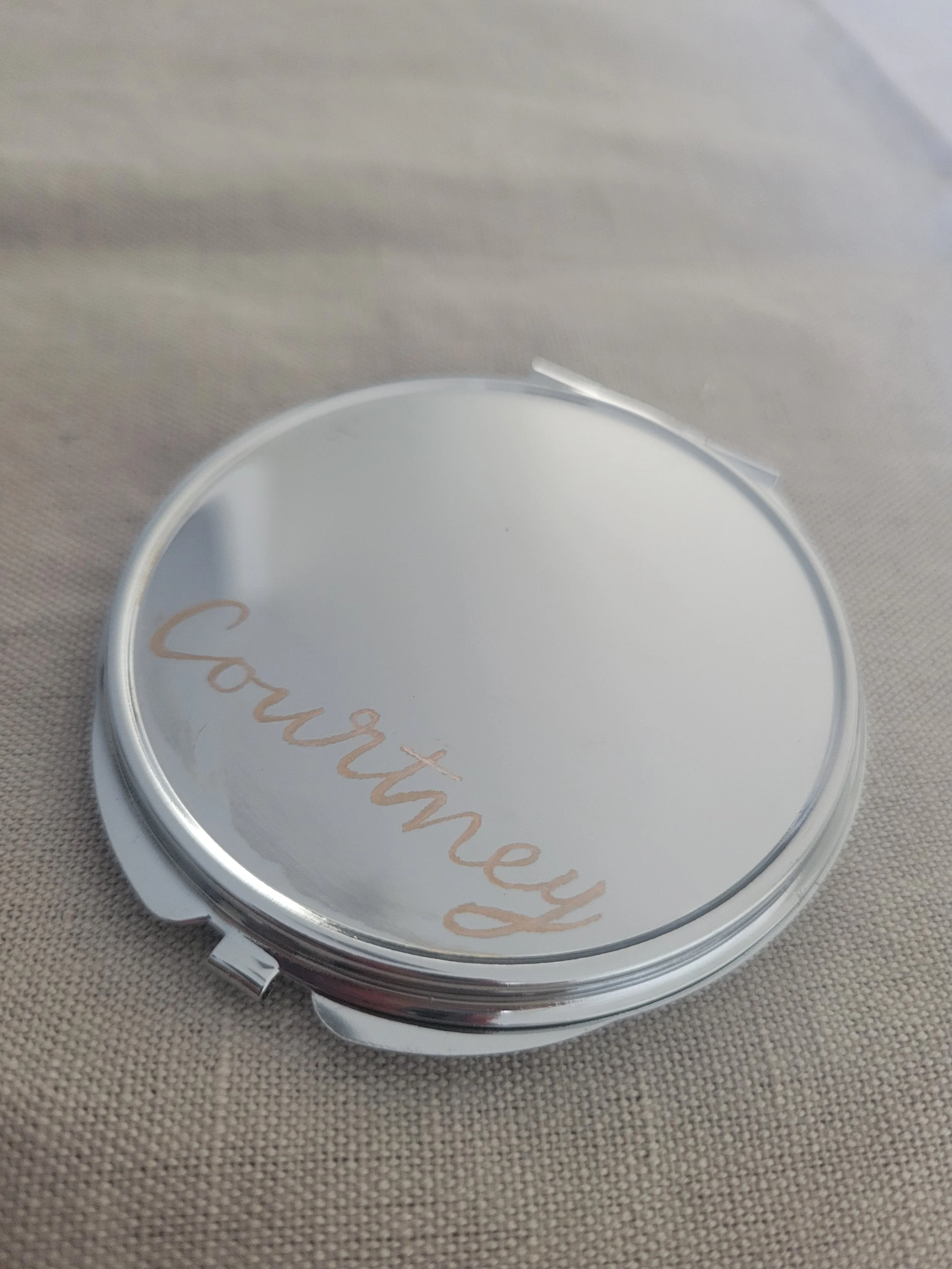 Hand-engraved silver compact mirror personalized with the name "Courtney" in rose gold calligraphy script. Custom bridesmaid gift and wedding favour by À La Court Calligraphy, based in Nice.
