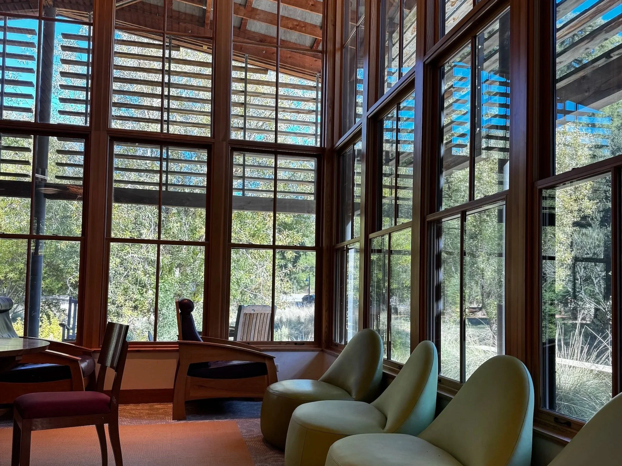 Portola Valley 图书馆内部空间，大型木框落地窗将自然景色引入室内，展现其 LEED 白金级的环保建筑特色。