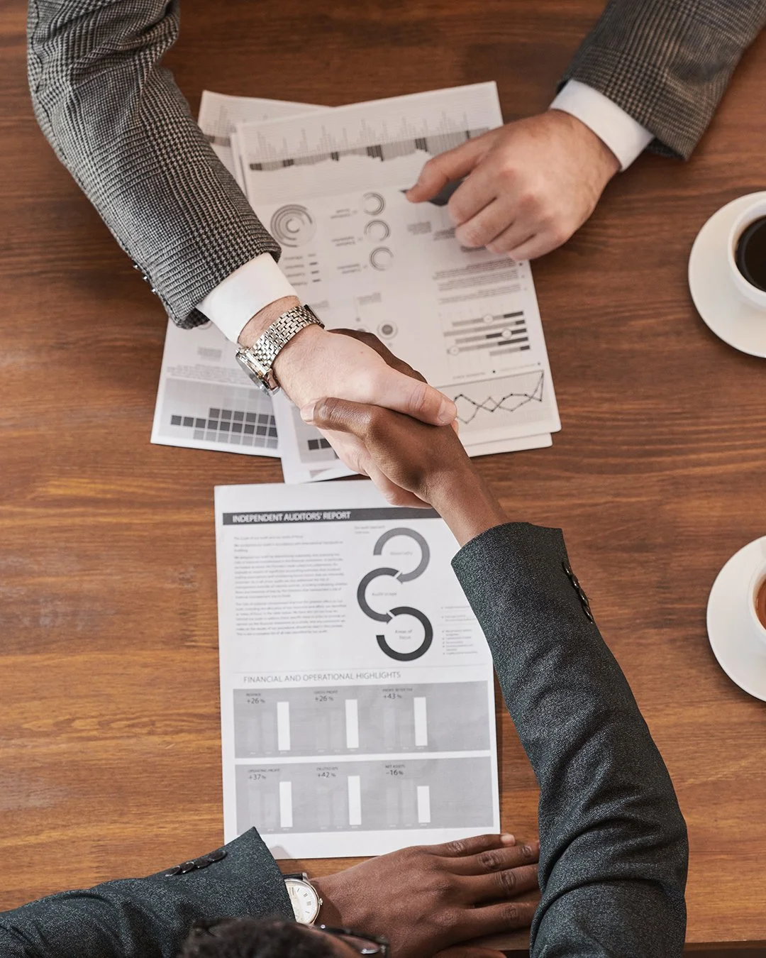 Two individuals shaking hands over business deal