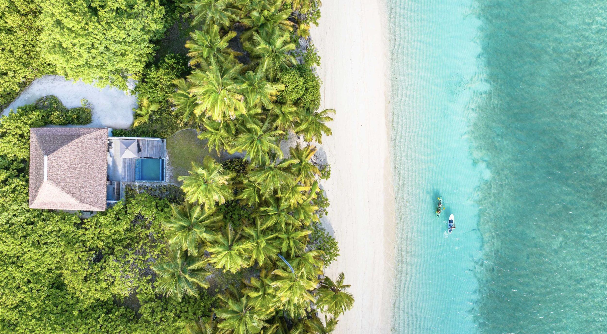 Snow-capped mountains under an cloudy sky with grassy hills in the foreground.