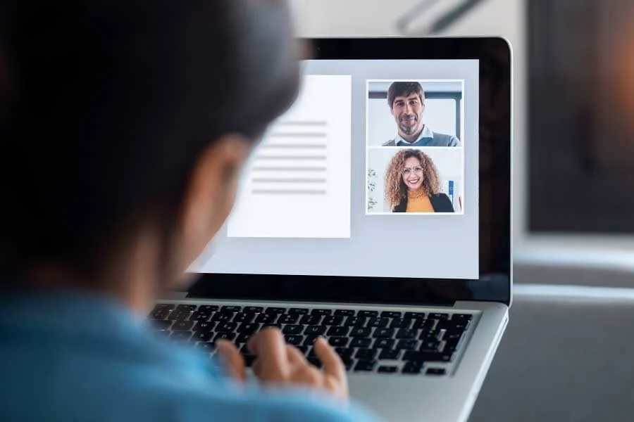 Person participating in a video call on a laptop with two people visible on the screen.