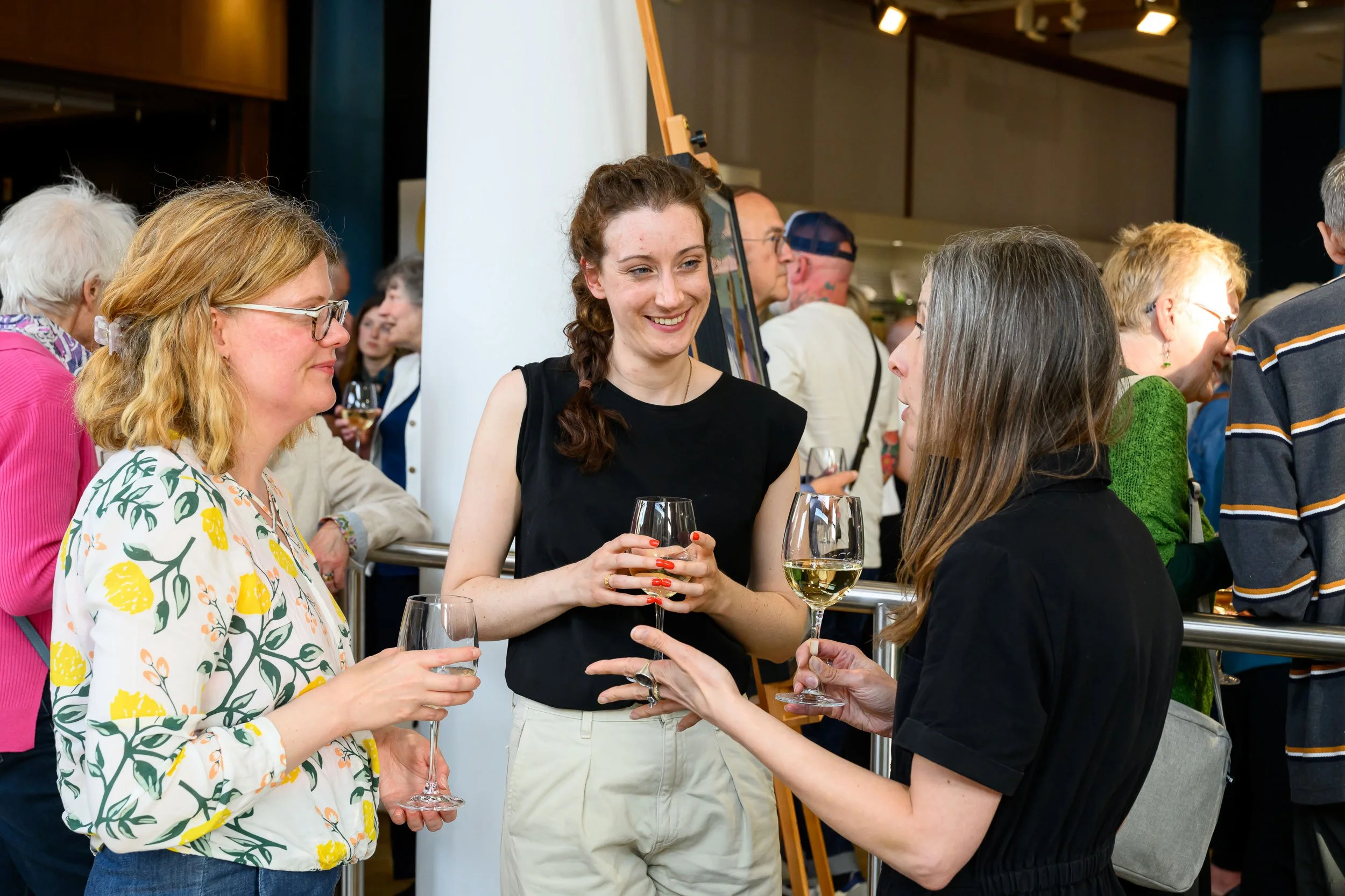 Group of women socializing and drinking white wine at an indoor event.