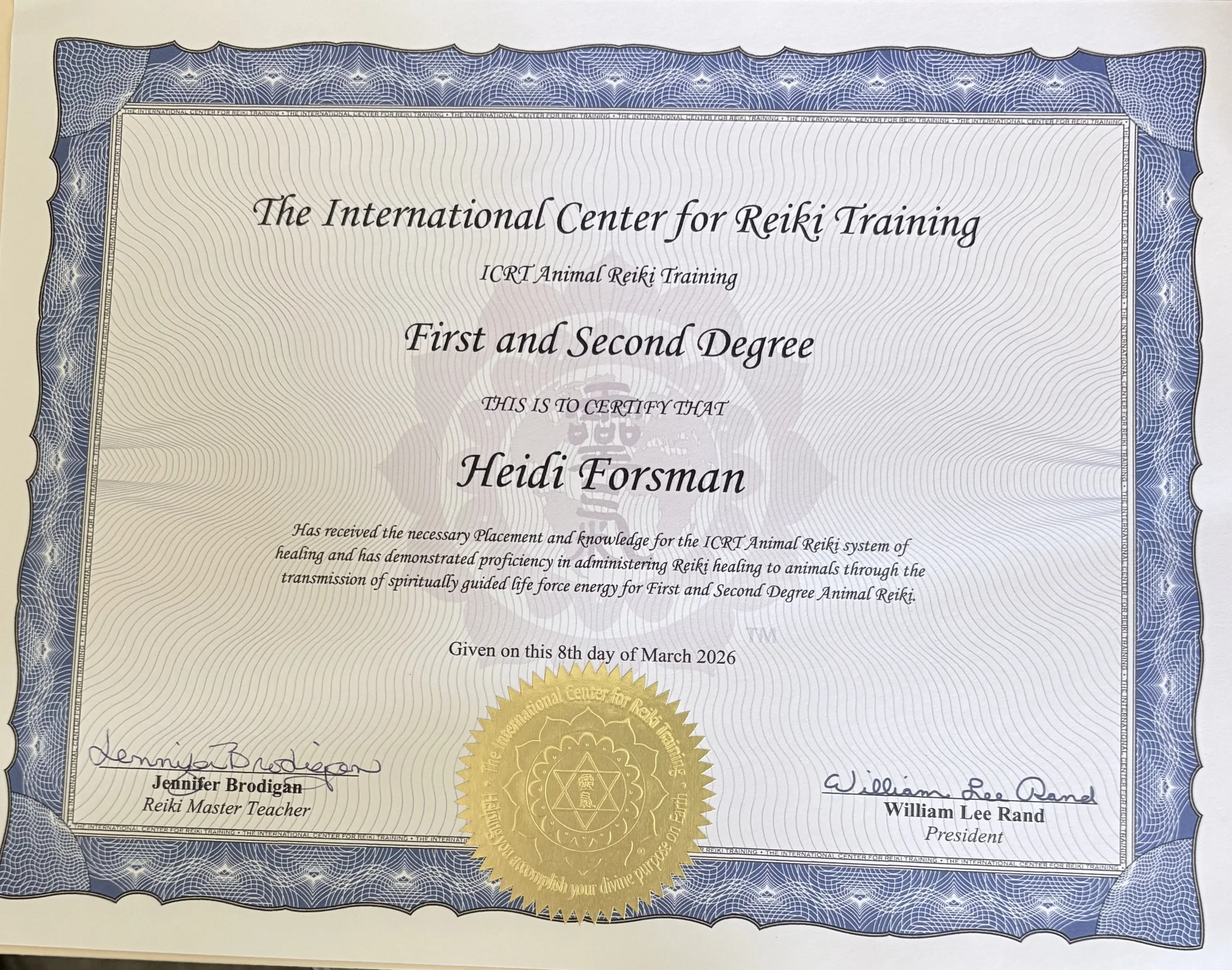 Certificate from The International Center for Reiki Training awarded to Heidi Forsman for First and Second Degree, dated March 8, 2026, with signatures and a gold seal, featuring a blue decorative border with web patterns.