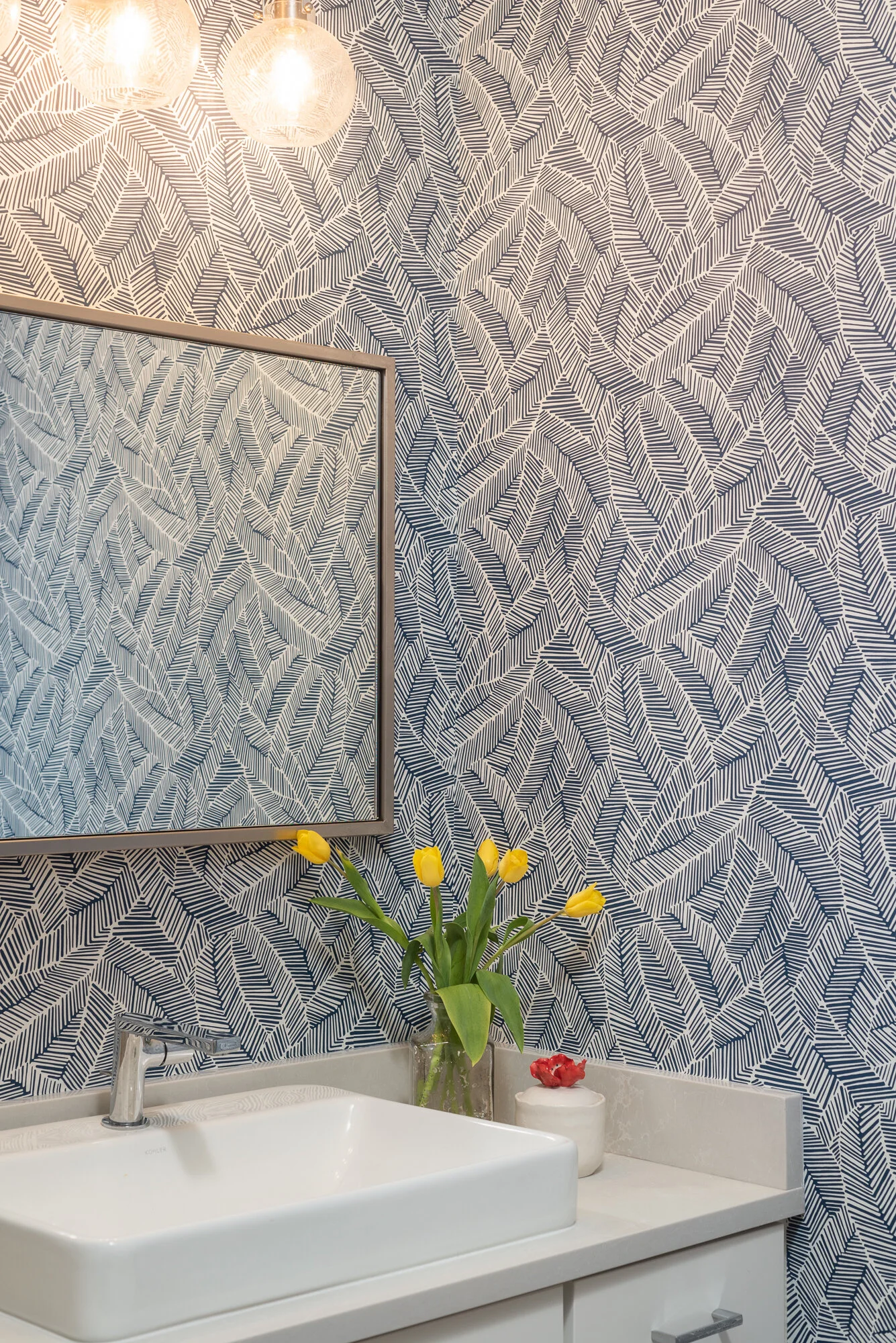 Bathroom blue pattern wallpaper with white sink and gold mirror