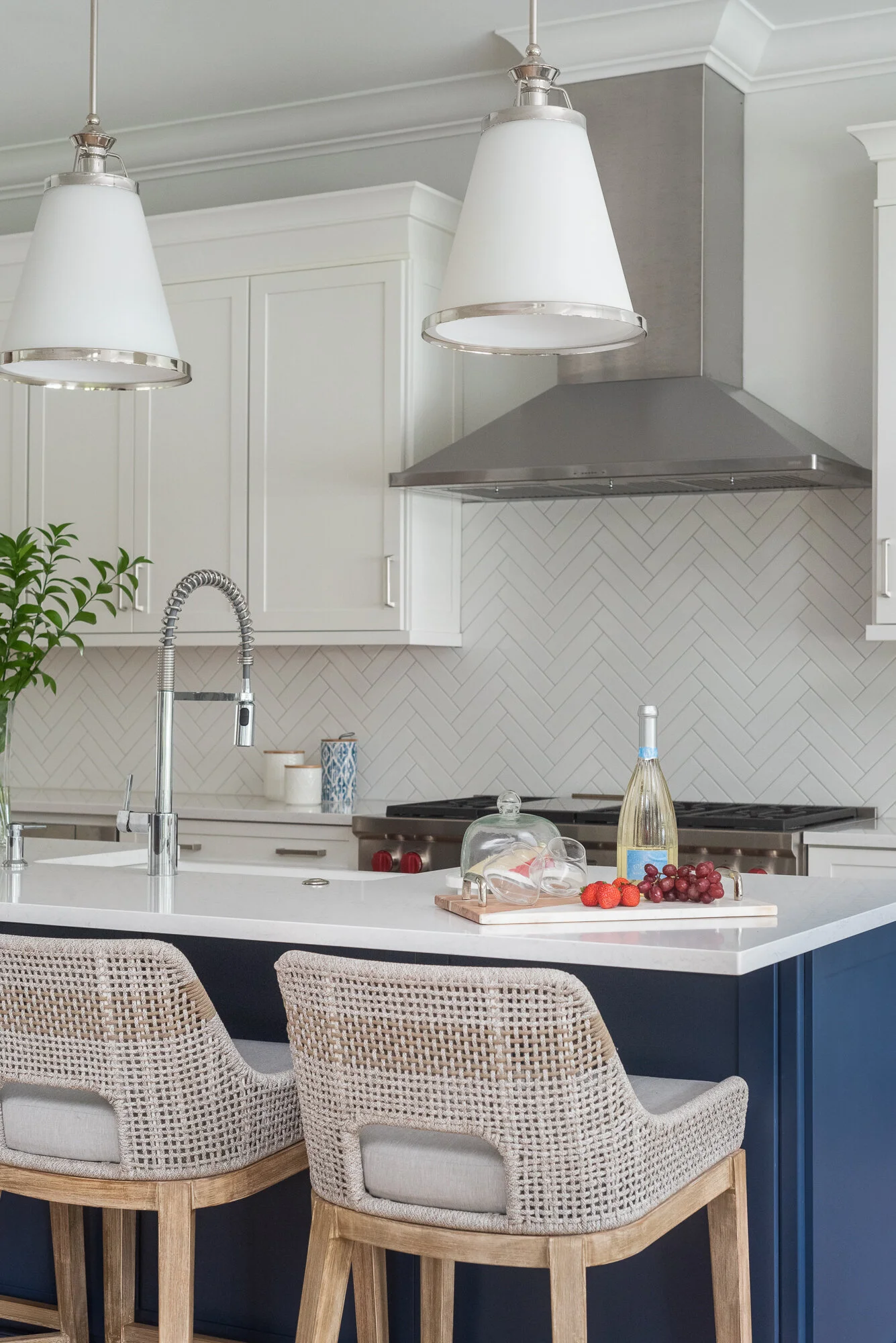 white and grey kitchen with woven bar stools and dark blue island