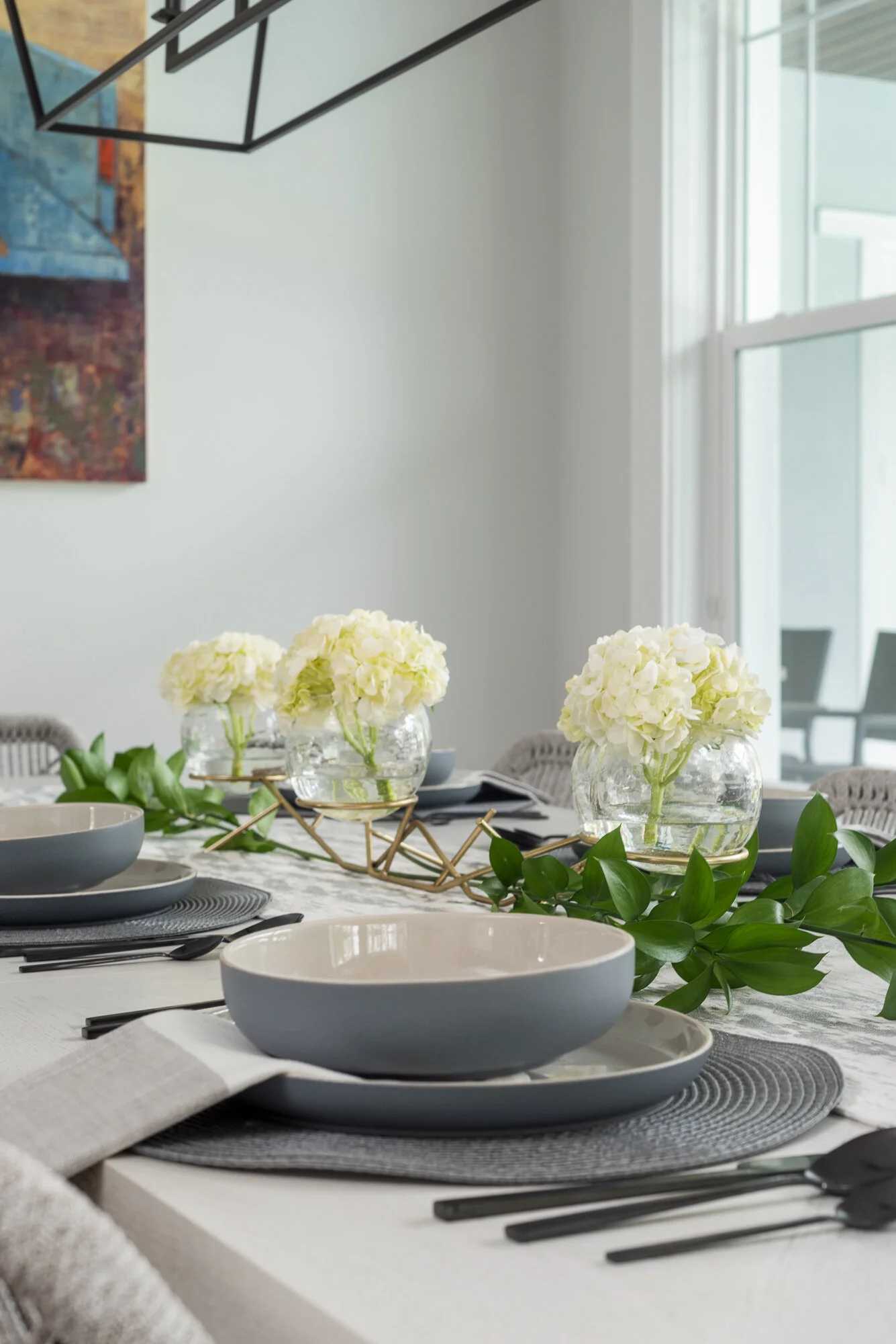 Dining room table scape with white flowers and black silverware 