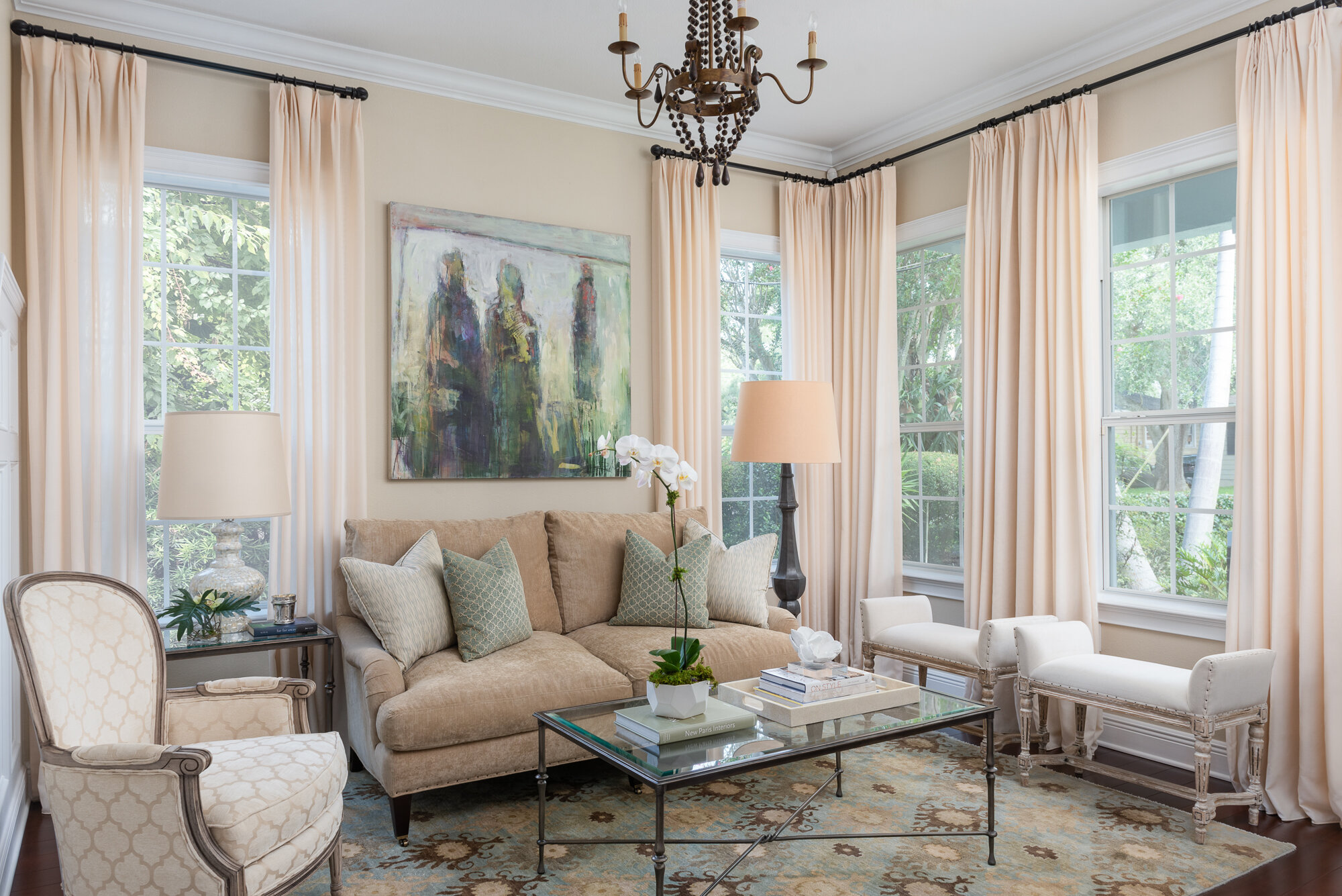 Traditional warm living room with couch, chandelier, coffee table, window treatment