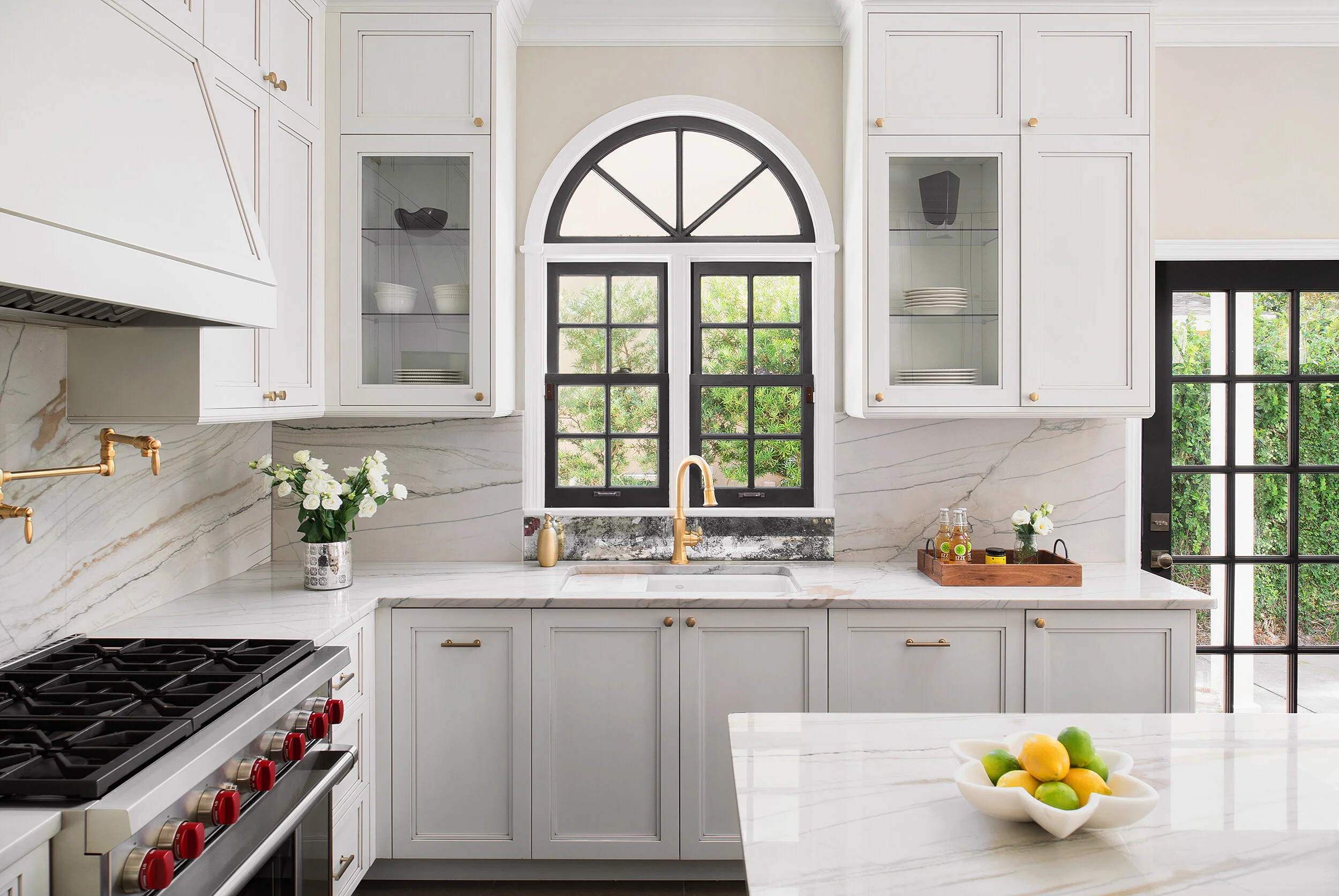 White marble kitchen stainless steel appliances and black window trimming endless backsplash and marble island