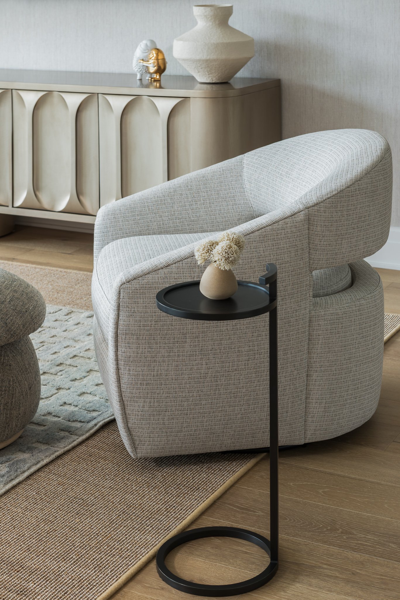  Grey upholstered chair beside a sculptural round pedestal table 