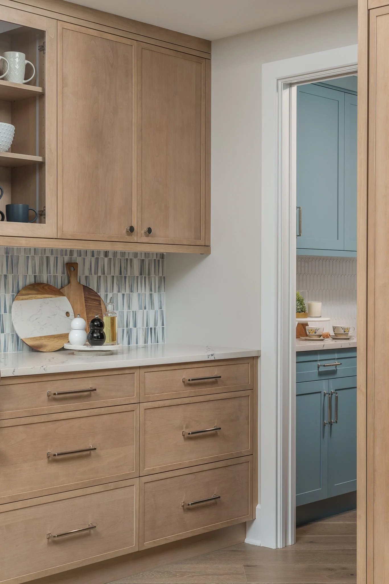Kitchen cabinetry with light wood and blue cabinets, decorated with tea cups, plates, and a cutting board.