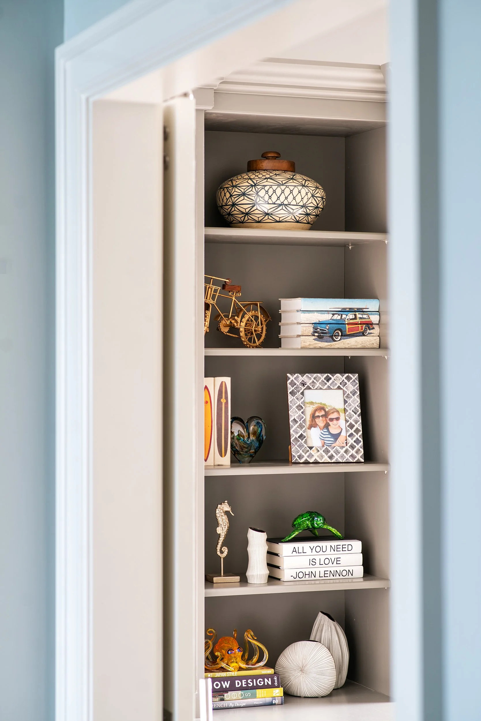 A built-in bookshelf with various decorative items and framed photographs.