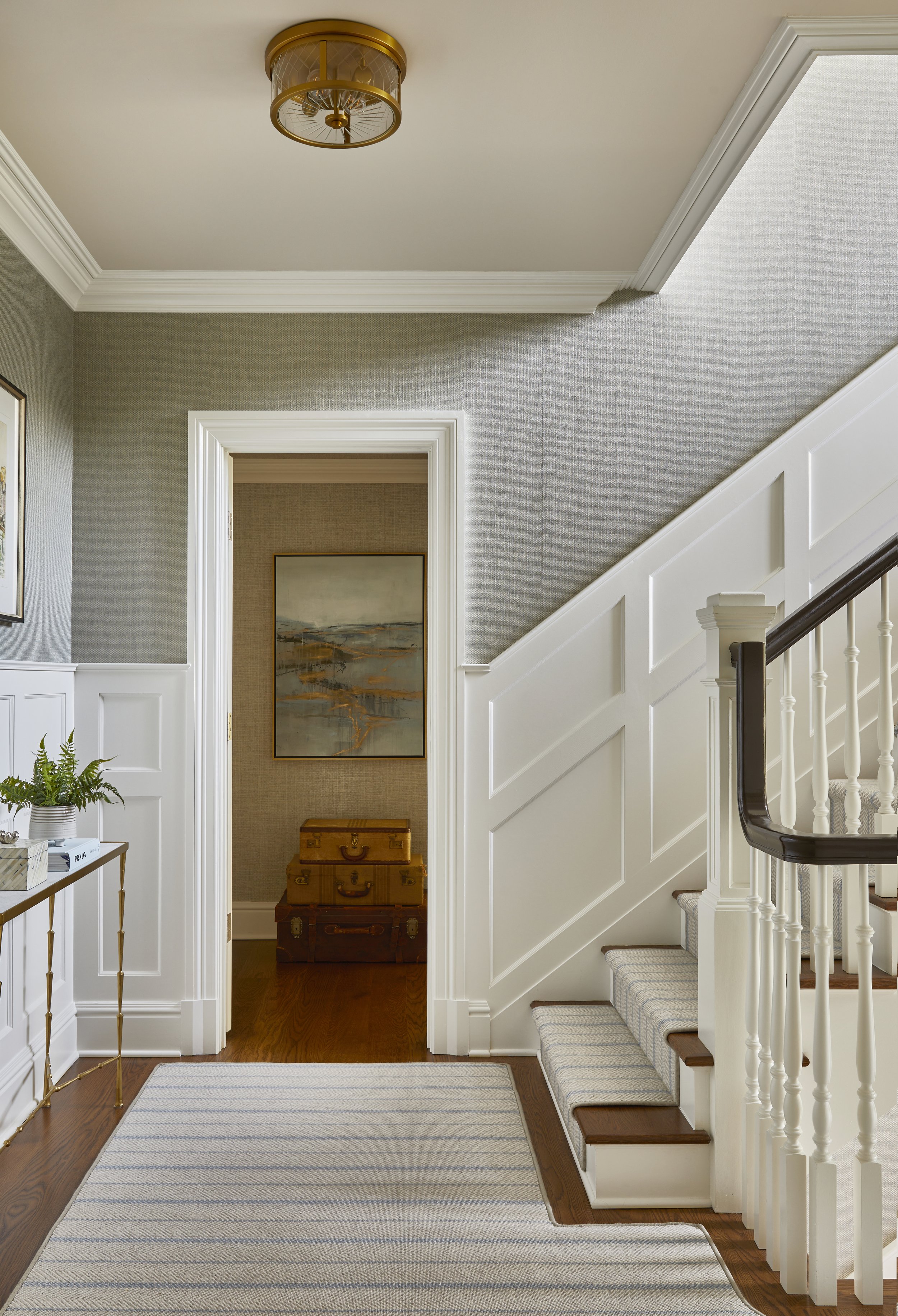 Entryway with staircase, framed artwork, and storage trunks.