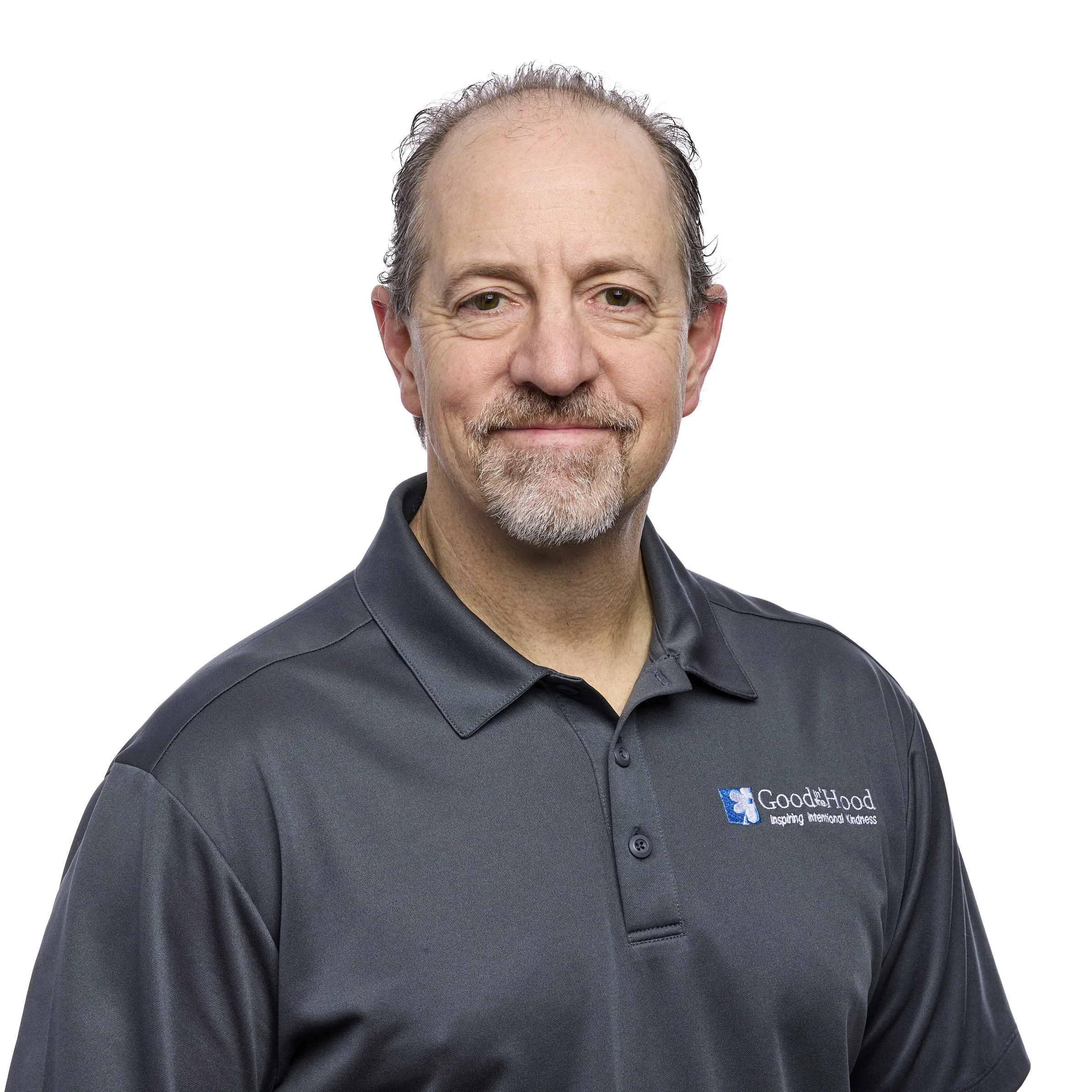Middle-aged man with a beard and glasses wearing a dark gray polo shirt with a Good Shepherd logo.