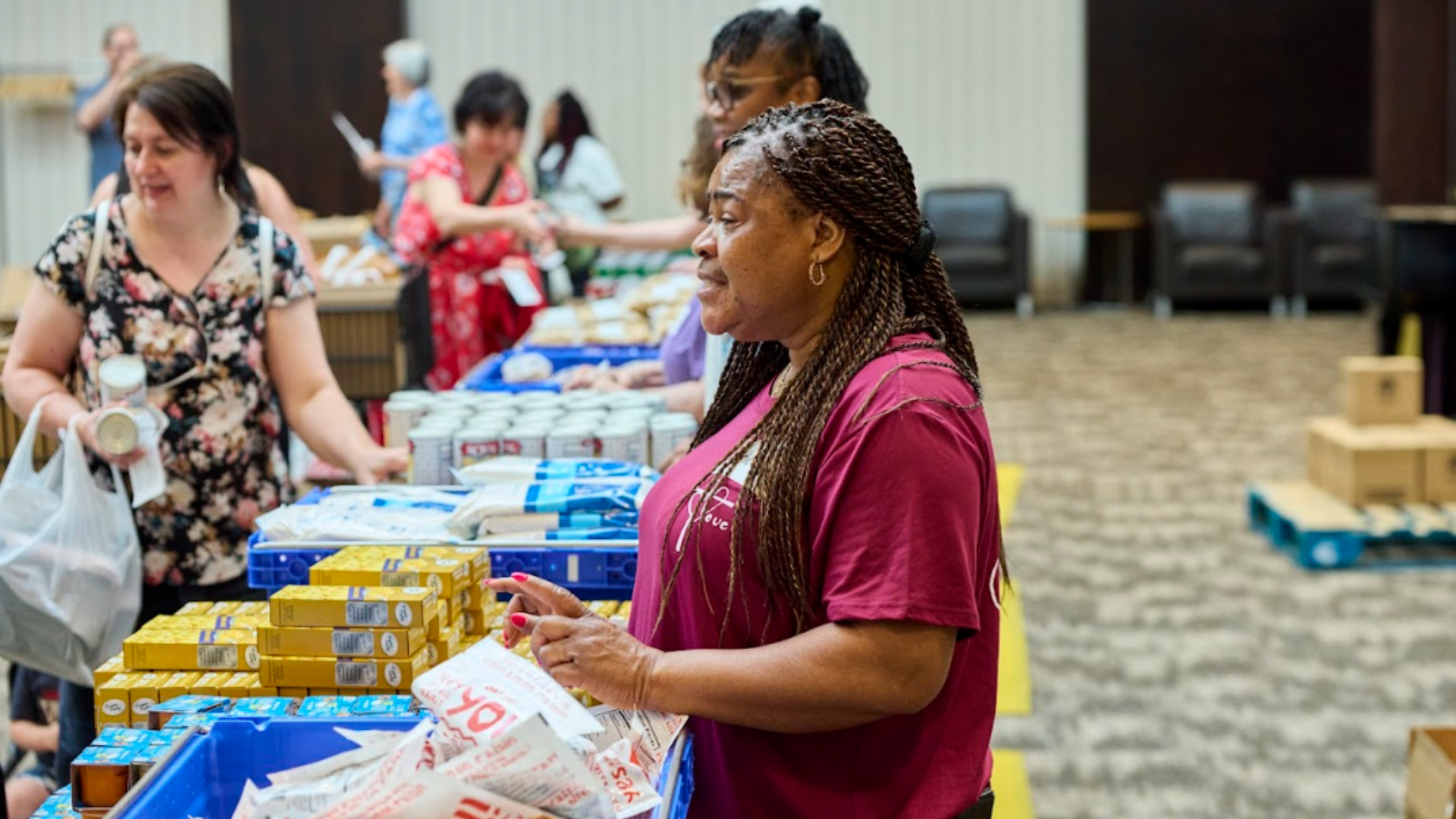 People shopping at a donation or food distribution event, selecting canned goods and pantry items.