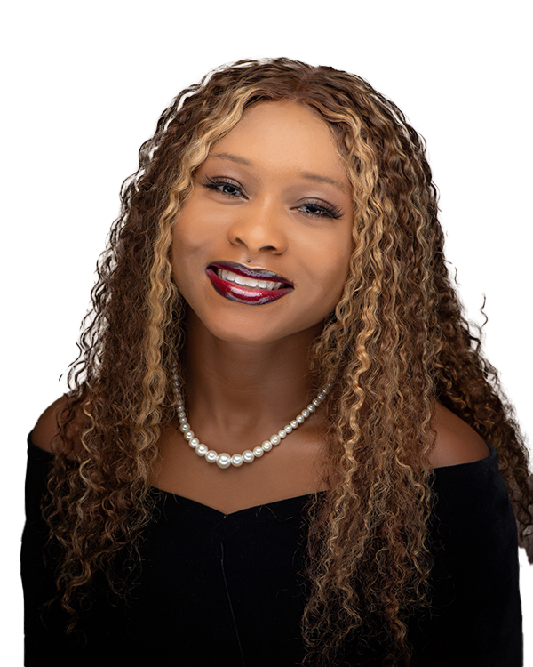 Portrait of a woman with long, curly blonde hair, wearing a black off-the-shoulder top, pearl necklace, and red lipstick, smiling at the camera.