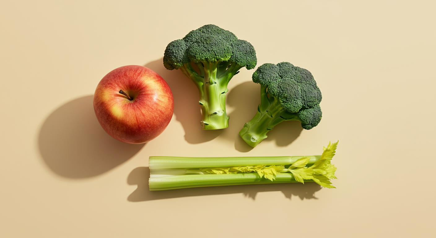 An apple, two broccoli florets, and two celery stalks are arranged on a beige surface with soft lighting.