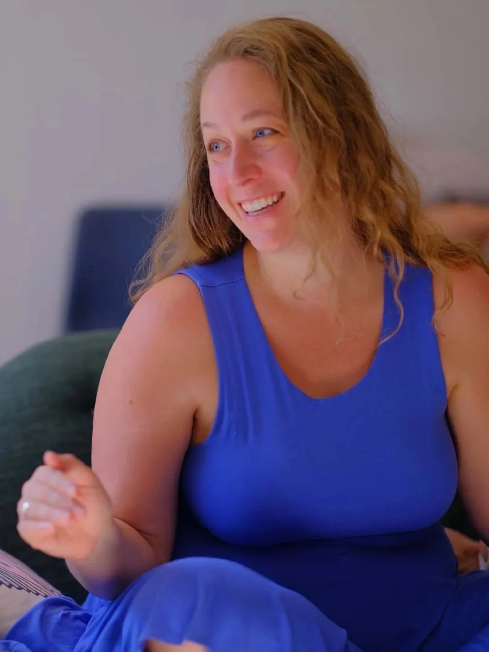 Annabeth Novitzki laughing on a green couch, mid-conversation