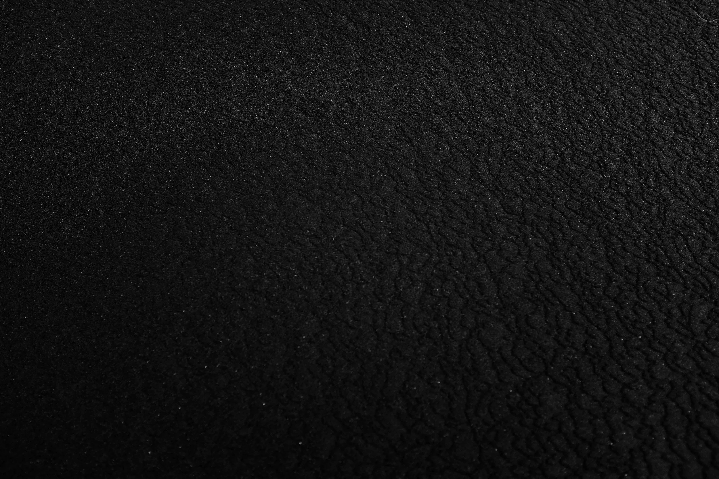 Close-up view of black textured surface with uneven, raised pattern.