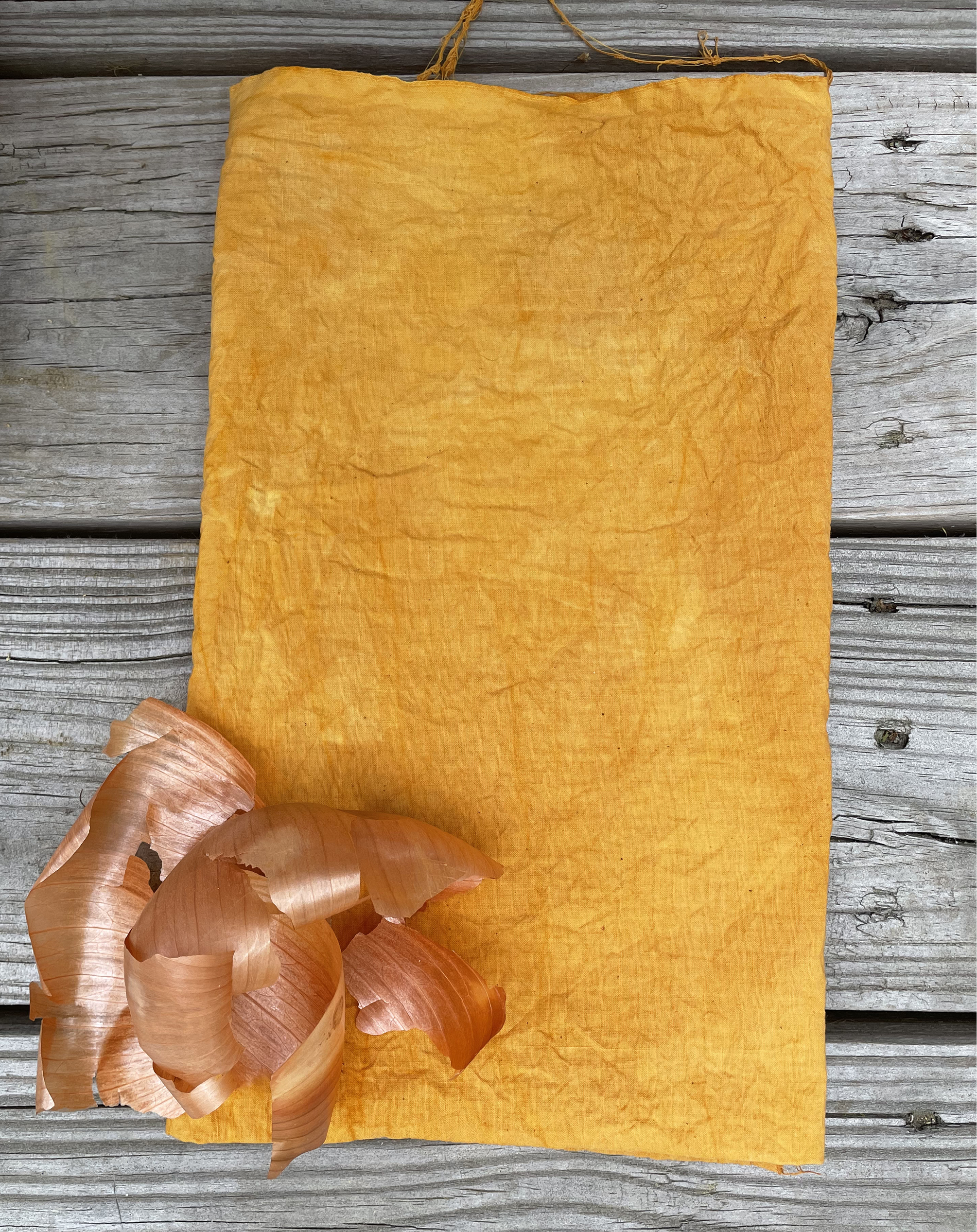A roll of orange paper with curled shavings, placed on a weathered wooden surface.