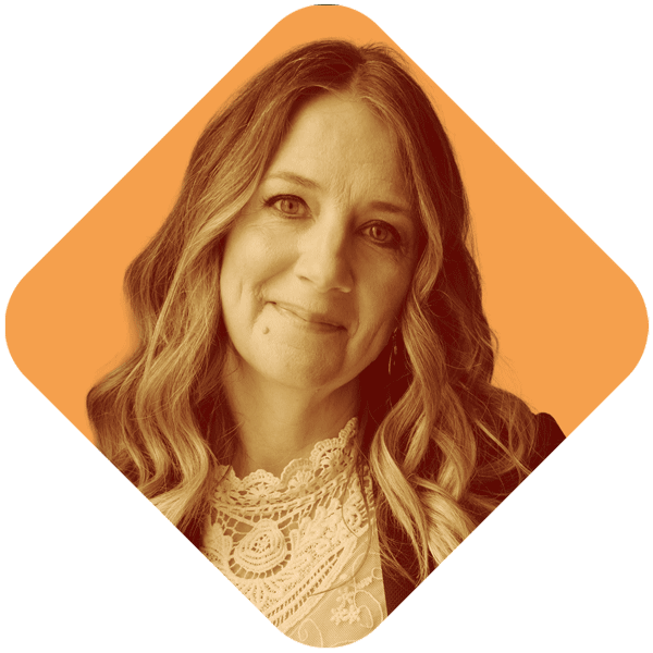 A woman with wavy hair smiling, wearing a lace top and a black jacket, against an orange background.