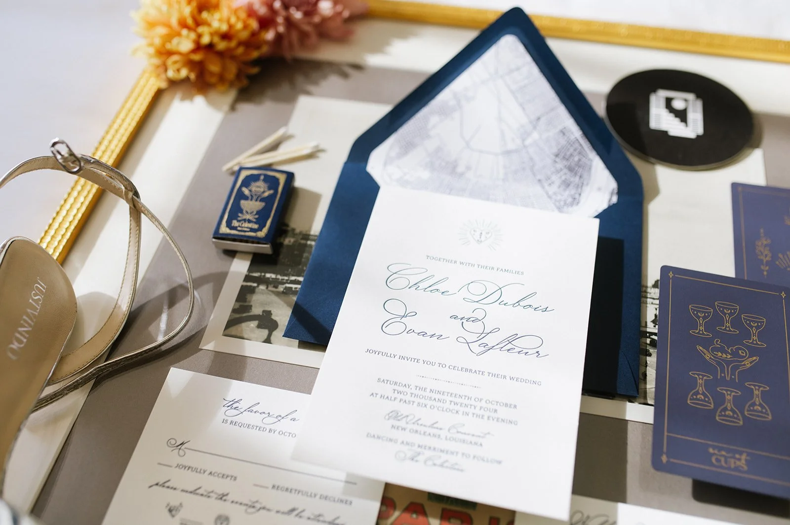 Wedding invitation, a pair of high heel shoes, matchboxes, a photo, and decorative items on a table.