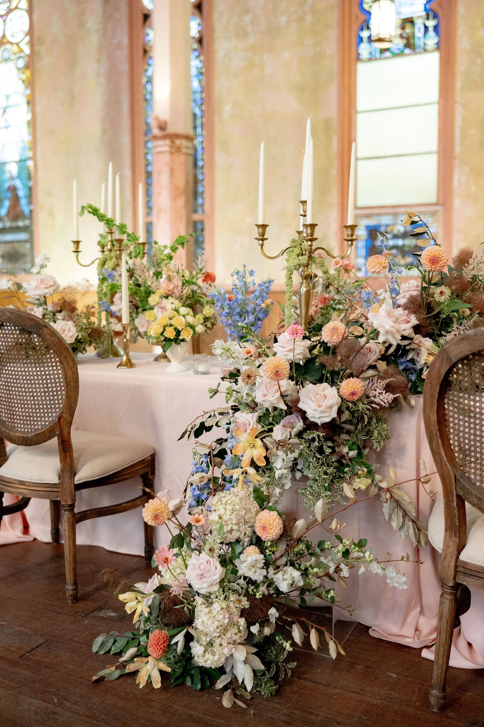 Elegant wedding table setup with floral centerpieces and candelabras in a decorated church or chapel.