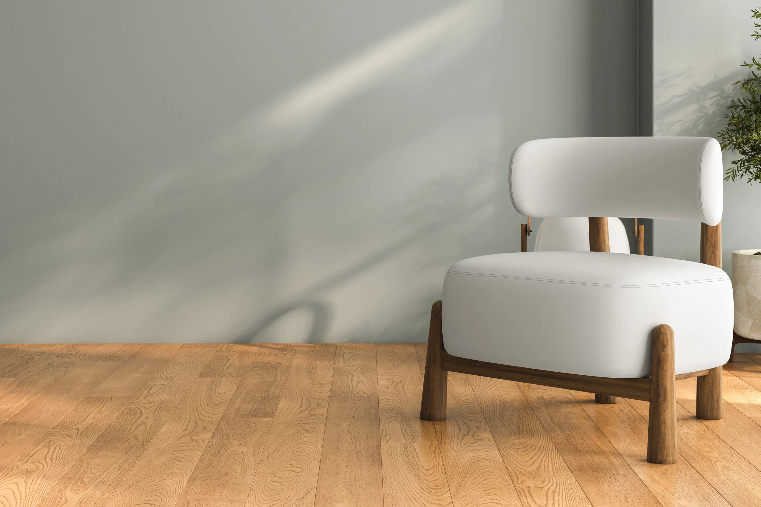 Modern white armchair with wooden legs next to a potted plant on a wooden floor.