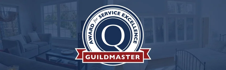 Certificate or award badge with the text "Guildmaster" and "Award for Service Excellence" overlaying a living room with a couch, coffee table, and windows.