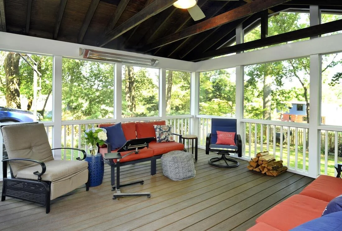  screened porch with outdoor furniture, wood pile, and view of trees.
