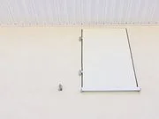 White wall with a closed white door and a small pipe or vent below it.