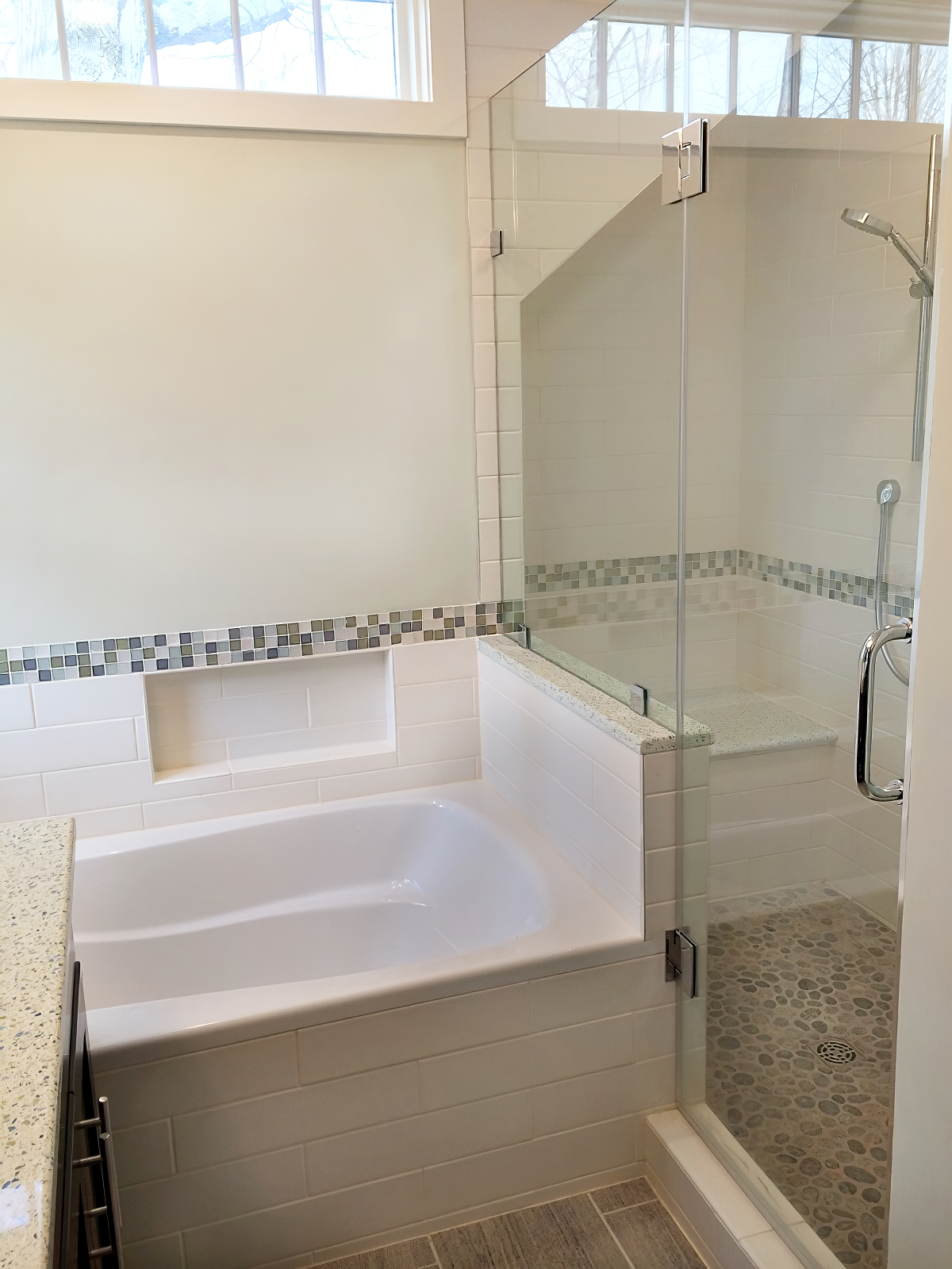 Bathroom with a bathtub and a separate glass-enclosed shower featuring pebble flooring.