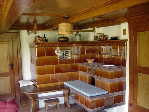 A corner of a cozy room with a brown tiled wall, wooden furniture, and decorative items on top.