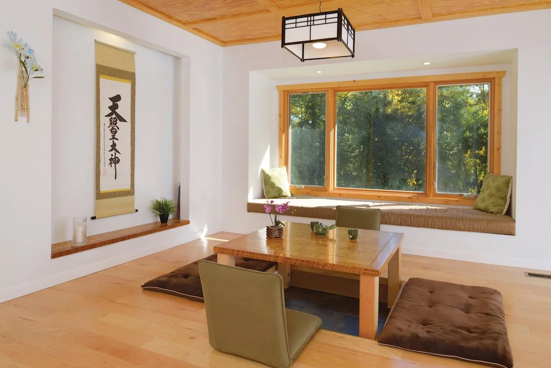 Living room with a large window seat, a wooden table with chairs, and traditional Asian decor.