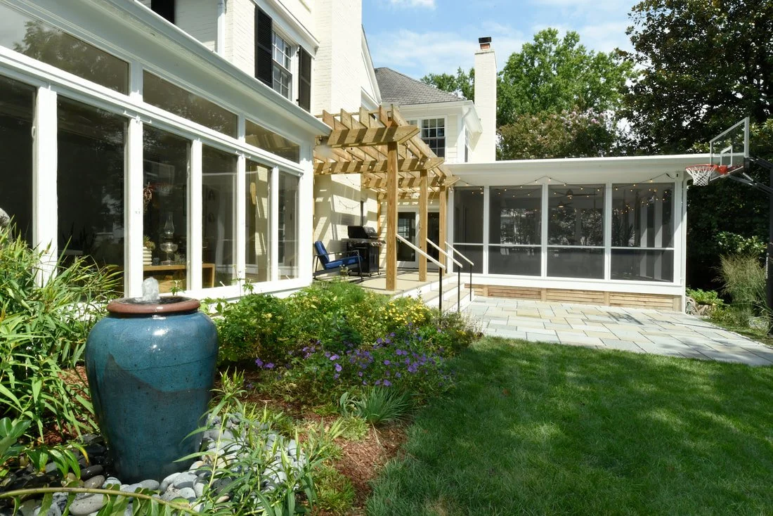 Backyard with potted water fountain, garden, patio, and screened porch with outdoor furniture.