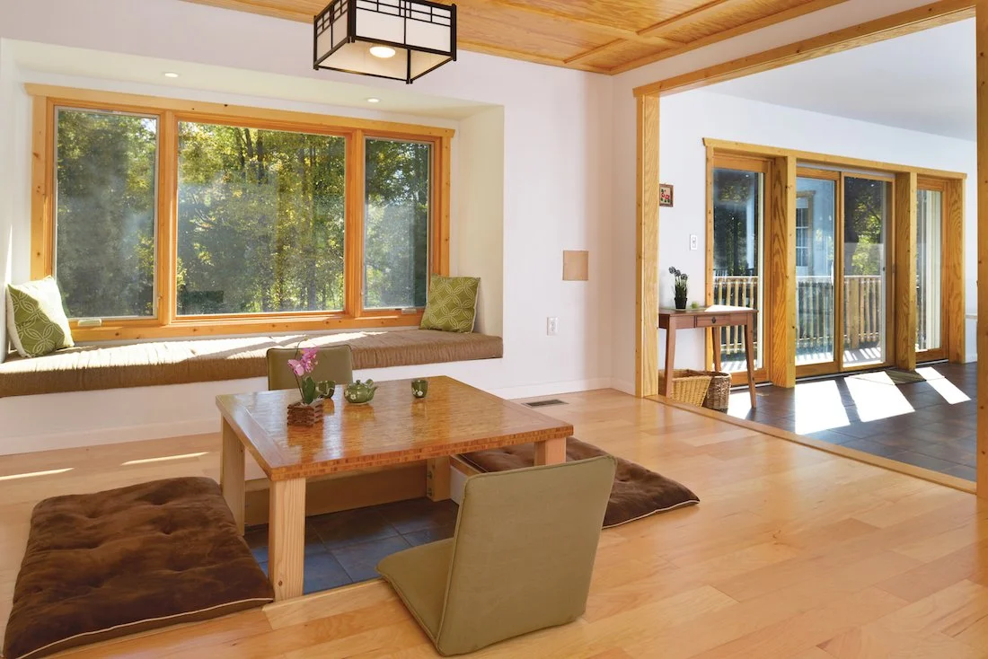 Bright living room with large window seat, wooden accents, and sliding glass doors leading to a balcony.