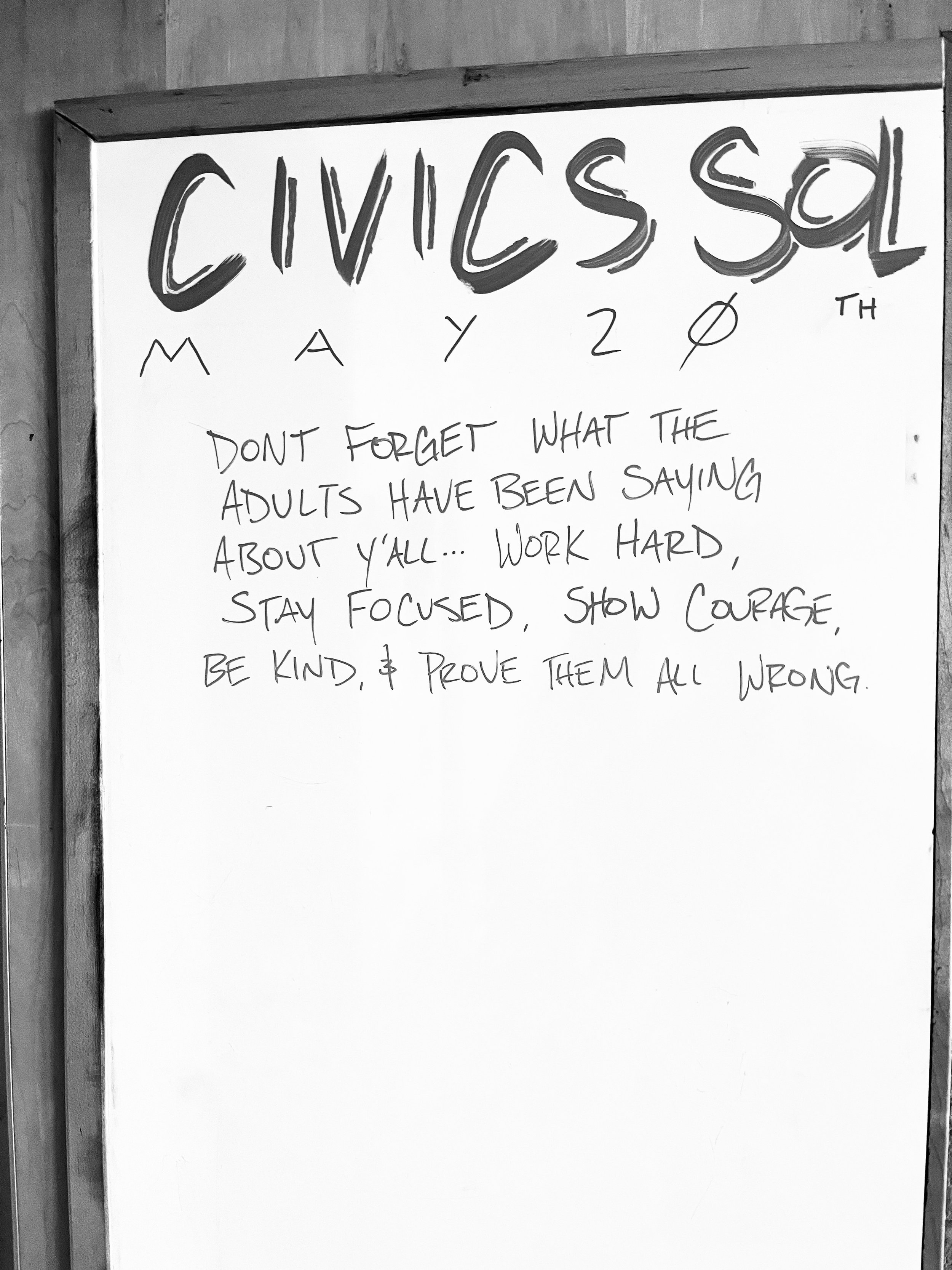 Whiteboard with the words 'CIVICS SAL' written in large, stylized letters at the top, and a message below that reads 'DON'T FORGET WHAT THE ADULTS HAVE BEEN SAYING ABOUT Y'ALL... WORK HARD, STAY FOCUSSED, SHOW COURAGE, BE KIND, & PROVE THEM ALL WRONG.'