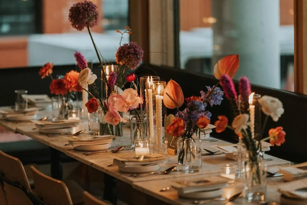 A table set for a dinner party with floral centerpieces and candles.