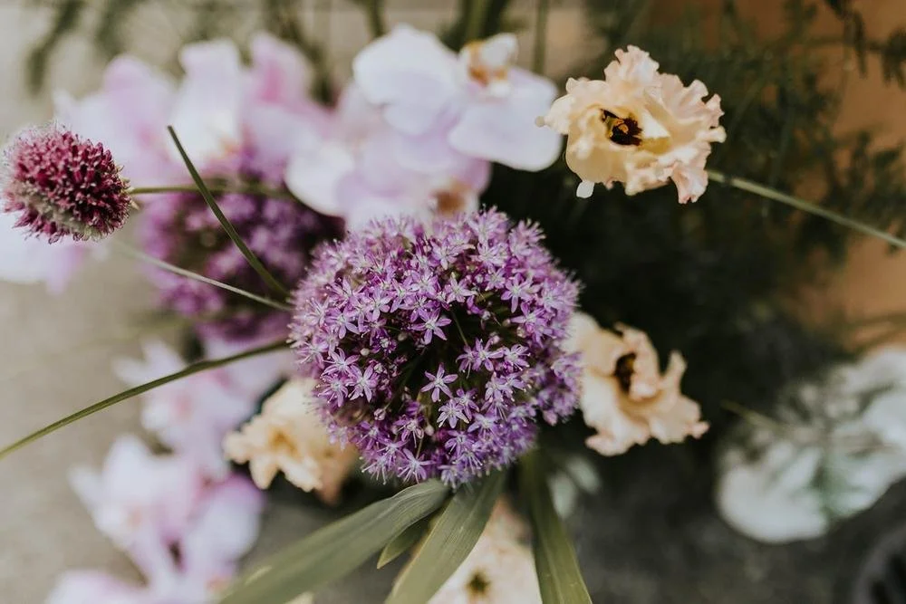 Close-up of a colorful bouquet of flowers, including purple, pink, and cream-colored blooms.