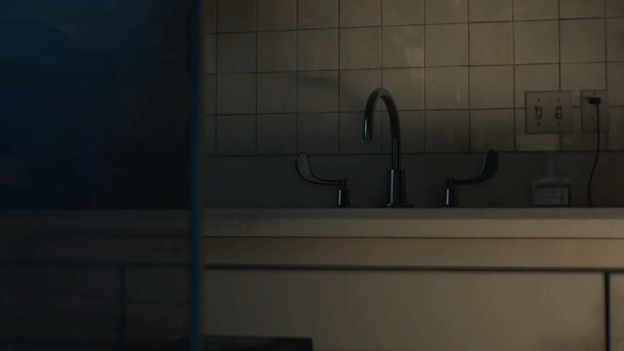 A GIF of a Dimly lit kitchen with a stainless steel faucet and beige tiled wall with a peeking Octopus 