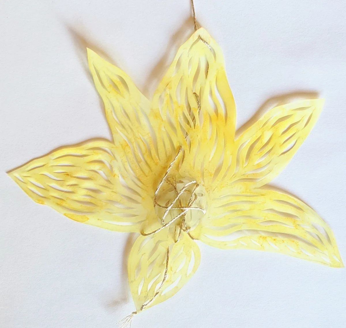 Yellow paper flower with detailed cutouts on white background.