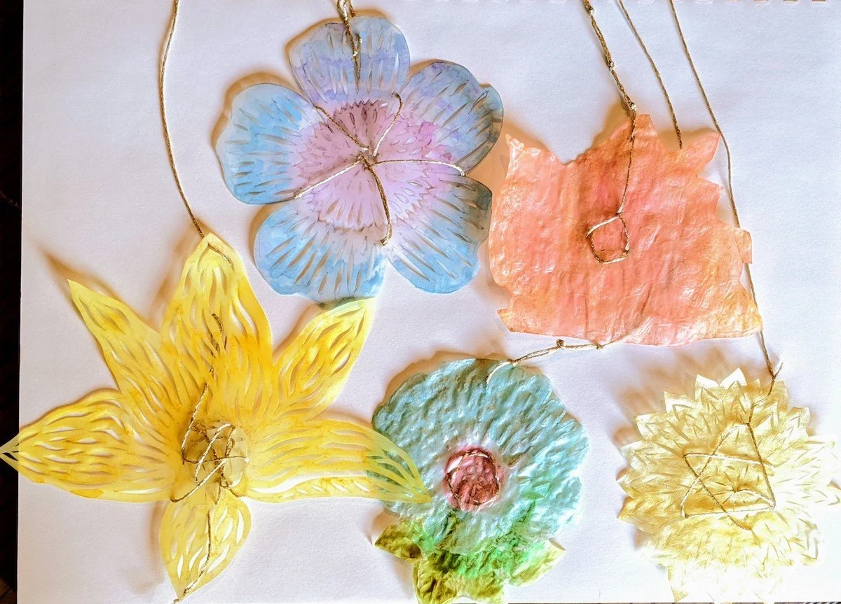 Colorful paper cutouts of various flowers with gold wire outlines, placed on a white surface.